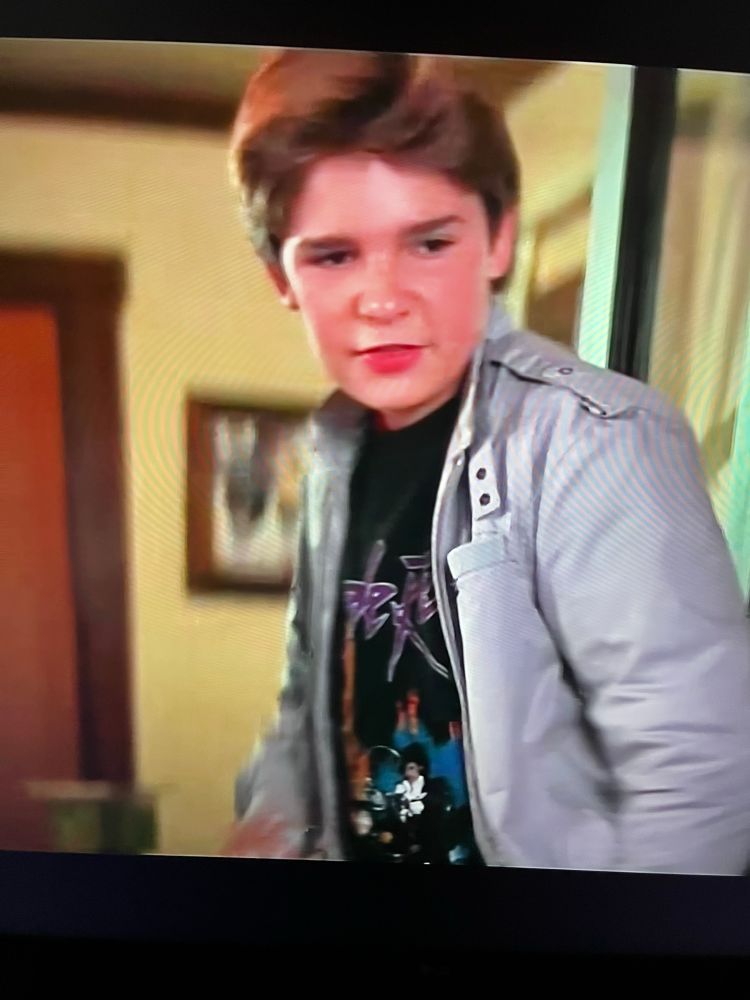 Corey Feldman in the movie goonies wearing a Prince purple rain T-shirt