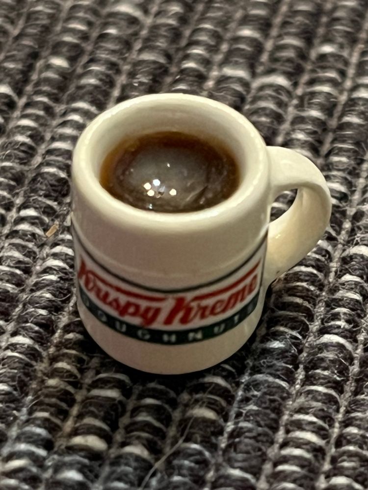 A miniature cup of coffee in a mug labeled Krispy Kreme