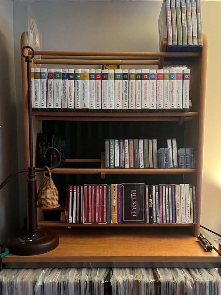 CD rack on top of record shelves. Some ps4 games, cassettes, walkmans, cds, caxixi, row of dave’s picks
