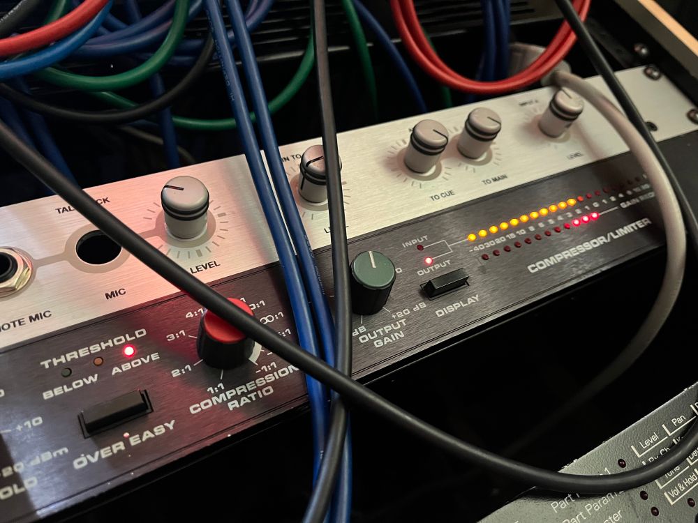 dbx 160x compressor in the desk, dangerous brain above, m1d1 modules below, patch cables a’danglin’ in black, blue, red, and green.