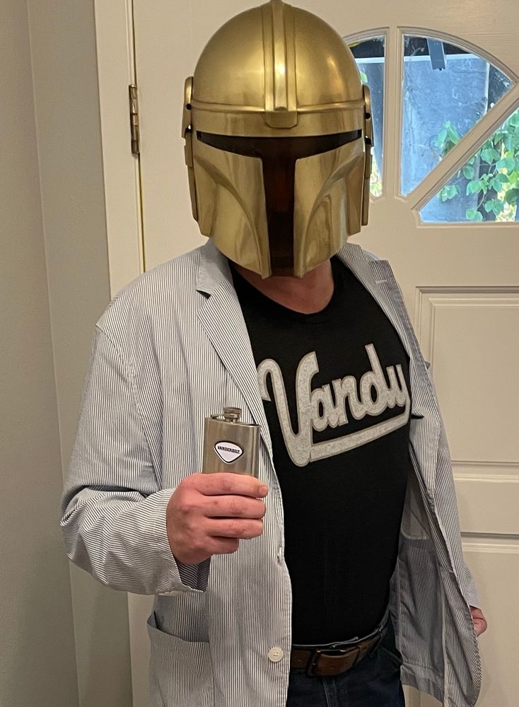 The Vandylorian. He wears jeans, cowboy boots (not visible), a throwback Vanderbilt t-shirt from Homefield, a seersucker blazer and a black and gold Mandalorian helmet. In his hand is a Vanderbilt flask. THIS IS V WAY. 