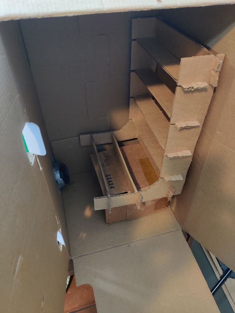 The drying rack from the previous post inside a vertical cardboard box with a blow dryer made to pass through the bottom corner and sealed with duct tape.