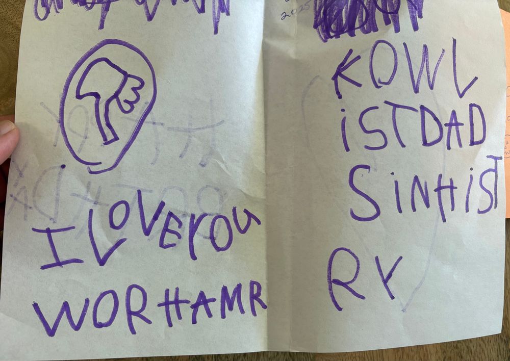 Card in child’s handwriting with a Warhammer logo reading “I Love You / WORHAMR / KOWLIST DAD IN HISTRY”