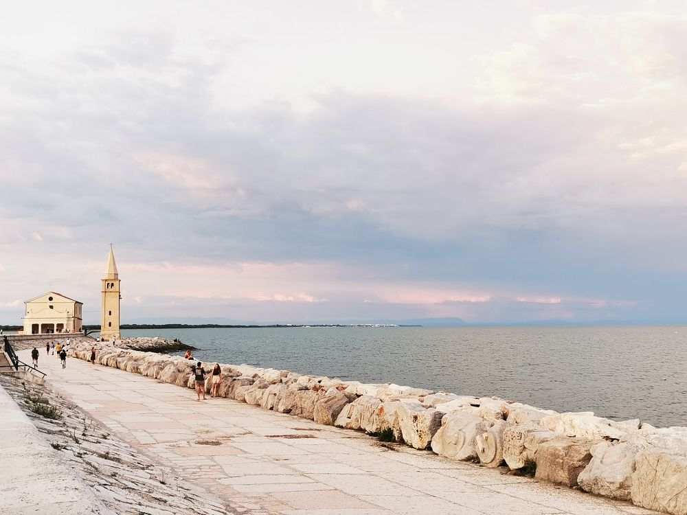 Pavement by the sea, old church in background, pastel colors sky