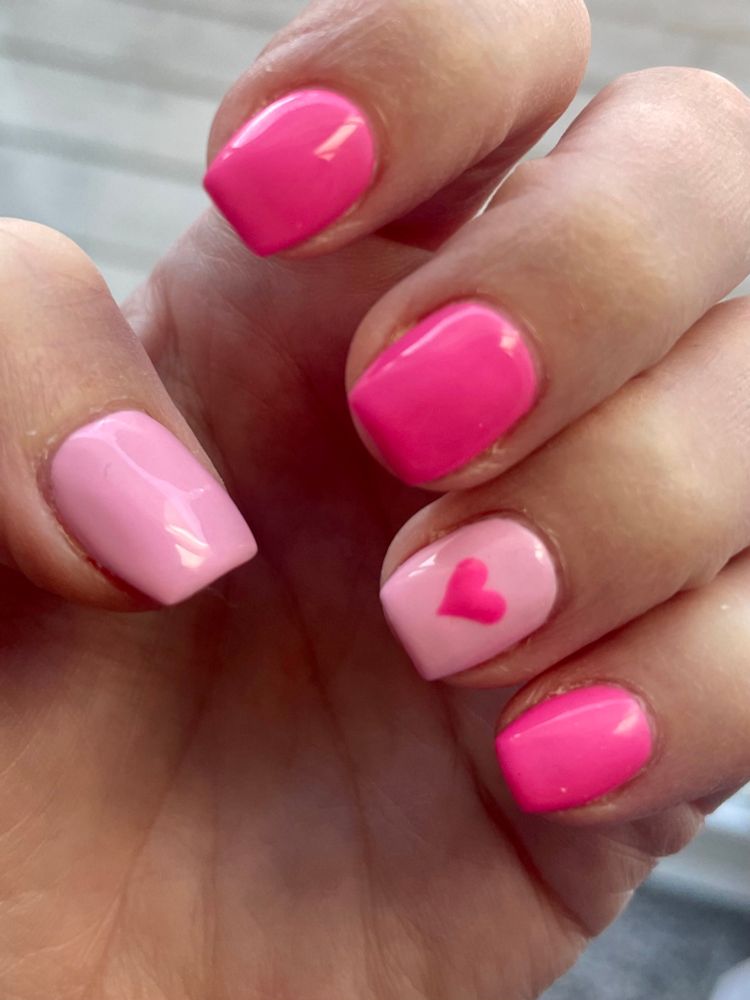 Short acrylic nails painted hot pink and bubblegum pink with heart design. 