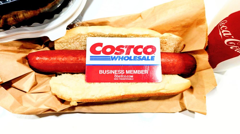 a Costco hot dog in  a hot dog bun on paper bag where the Costco hot dog usually is. there is a Costco membership on the hot dog lmao