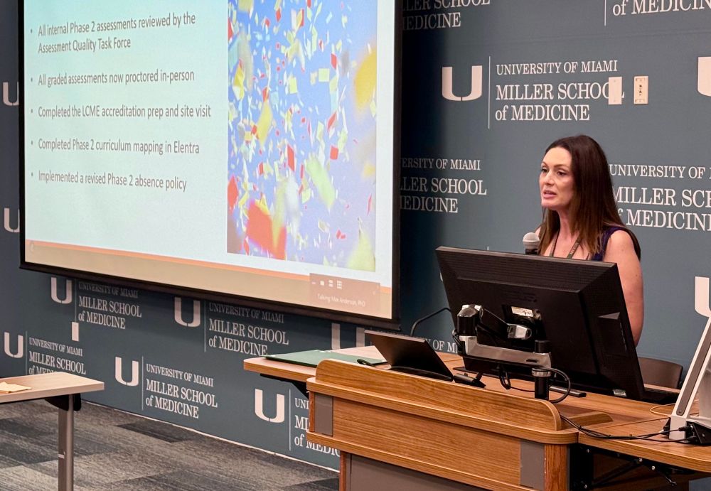 A woman is presenting slides on a large screen. 