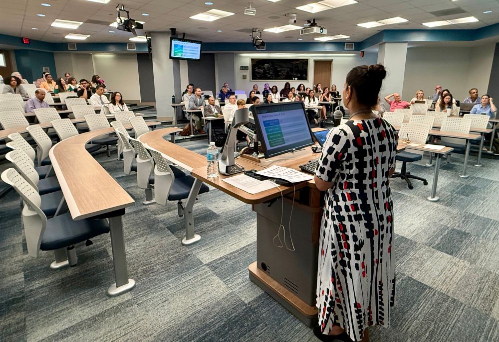 A woman is presenting to a group of people in an auditorium. 