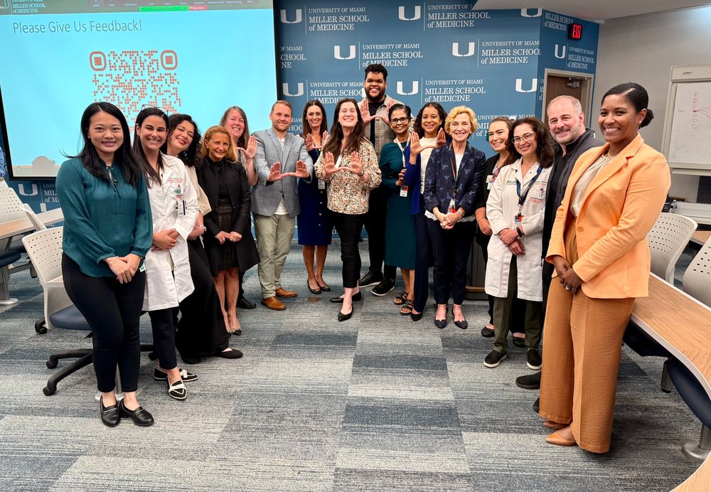 A group of people standing in front of a screen and a backdrop that says University of Miami Miller School of Medicine. 