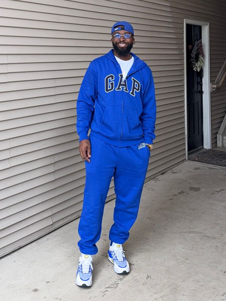 Standing; left hand in pocket; smiling; same fit.