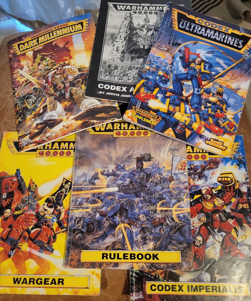 An array of warhammer 40,000 rulebooks from 2nd edition, piblisjed in the 90s, including the rulebook, wargear book, codex imperialis, codex army lists, codex: ultramarines and dark millenium.