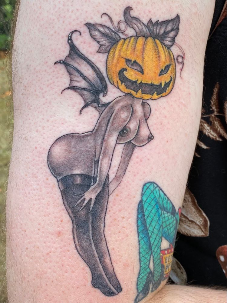 black and grey tattoo of a busty, thick-assed, jack-o’-lantern-faced, fairy demon woman. 