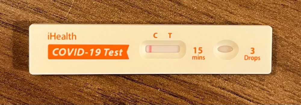 A COVID-19 test with a negative result, photographed against my hotel room end table.