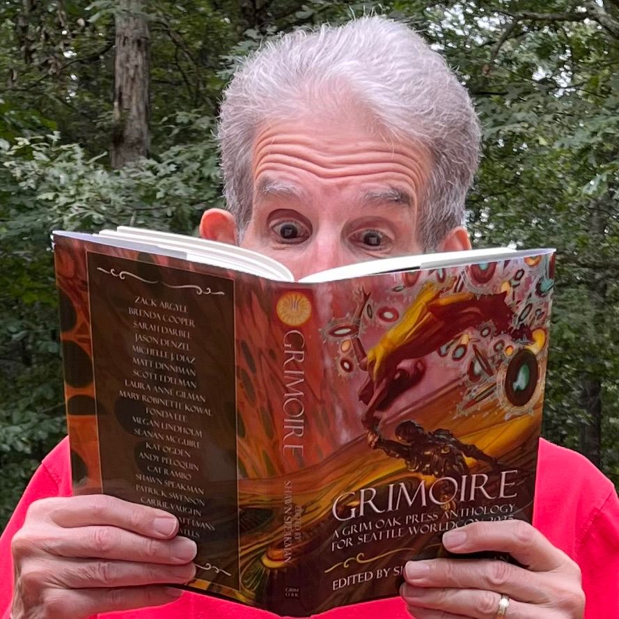 Me holding open the book and busy reading it. My hands are showing, but my head can only be seen above the bridge of any nose. The cover depicts a robot and human flying (dancing?) through space.