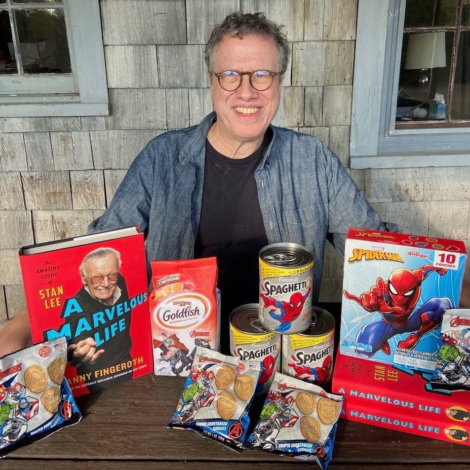 Danny posing with boxes and cans of all the Marvel-branded foods we ate during out meal: Avengers Goldfish, Spider-Man SpaghettiOs, Avengers Shortbread Cookies, and Spider-Man Fruit-Flavored Gummis. Plus a copy of his book Stan Lee: A Marvelous Life.