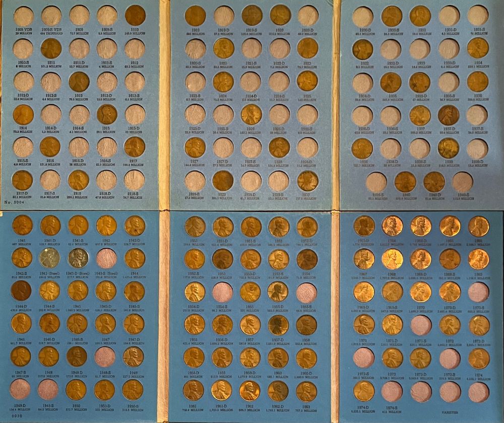 Two open trifold books for collectors, one atop the other. The upper one has slots for 1909 through 1940, the lower one 1940 through 1974. The upper one is perhaps a third filled, and the lower one perhaps 85%.