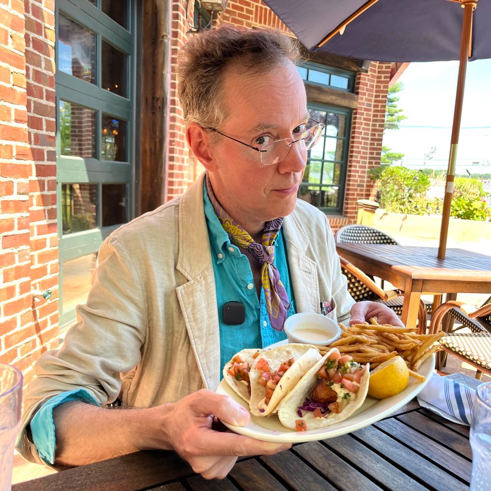 Richard looking at me warily while holding up his plate of fish tacos and fries.