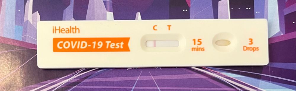 COVID-19 test with a negative result photographed against a detail of a purple image of a futuristic city.