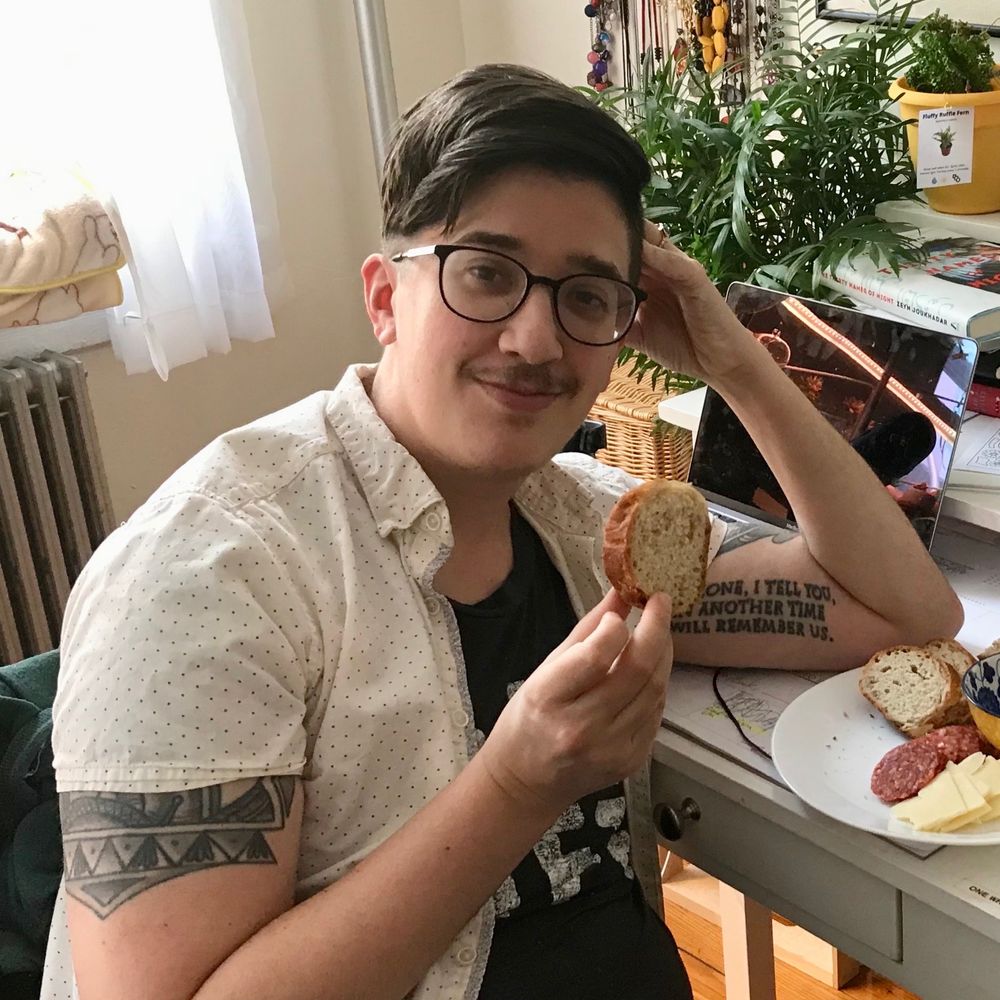 Nino, a charcuterie plate by one elbow, holding up a slice of Prosciutto Bread.