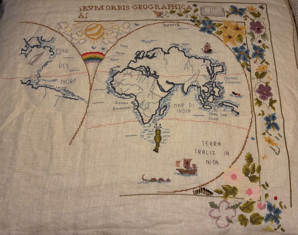 Photo of a cross stitch mid way done - it is an old map with floral border and other embellishments 