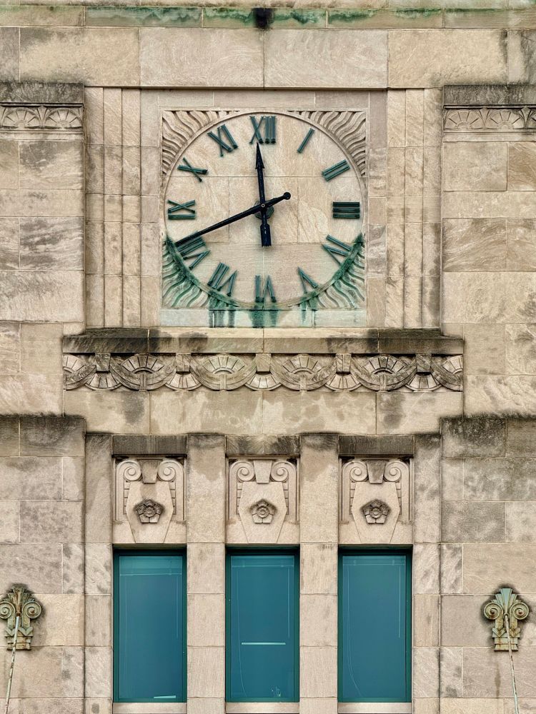 Close up on the clock, with wavy lines emanating from it. Some of the green Roman numerals are kind of melting off the clock 