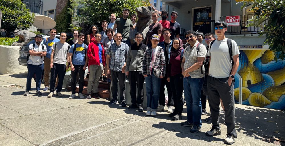 A group (subset of the attendees), lined up in the street, in front of a wooden bear sculpture