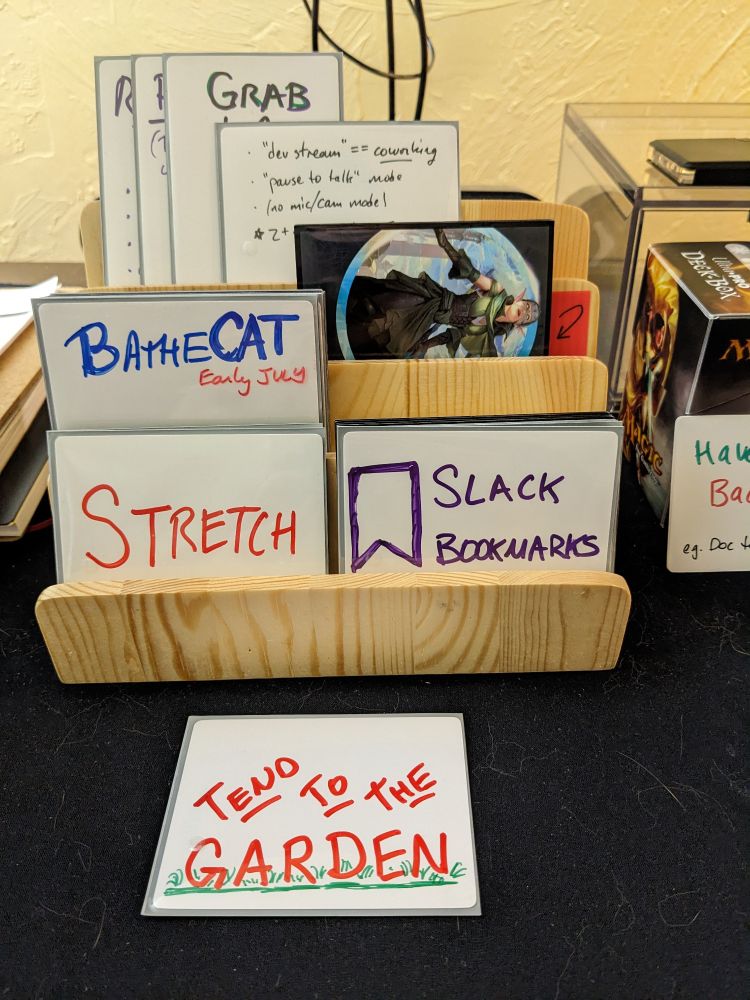 Some white proxy cards with large bold colorful marker lettering. On wooden stand, arranged on tiers.

Examples: "Bathe Cat", "Stretch", "Tend To The Garden"