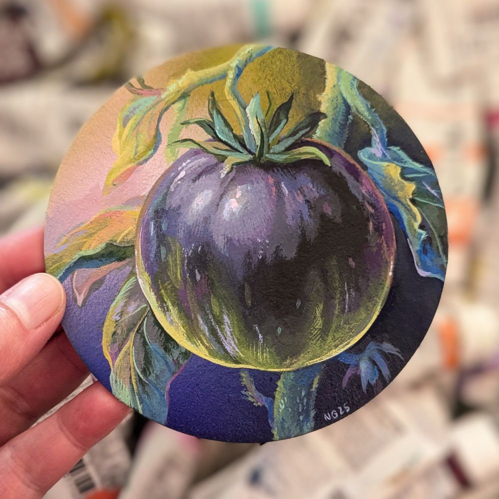Artist holding circular painting featuring a dark purple tomato with some green.