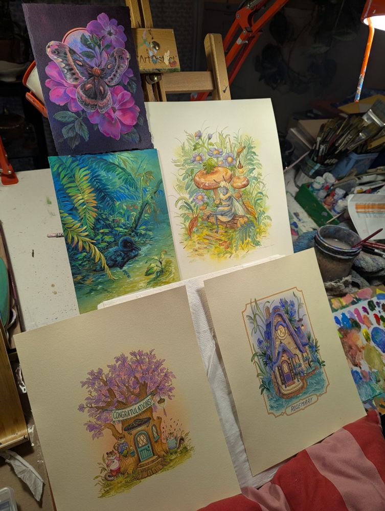 5 paintings on easel with messy art desk in background 