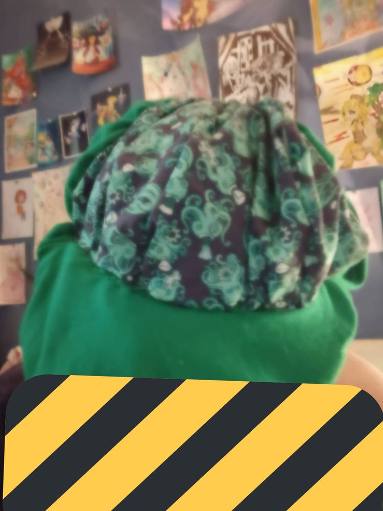 Casquette gavroche avec des motifs poulpes verts et bleus et du tissu vert. Vue de haut étant portée. Un emoji masque le visage