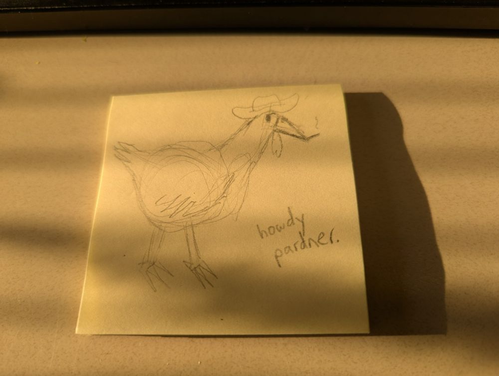 A poorly drawn chicken dressed as a cowboy on a yellow sticky note pad that says "howdy pardner"