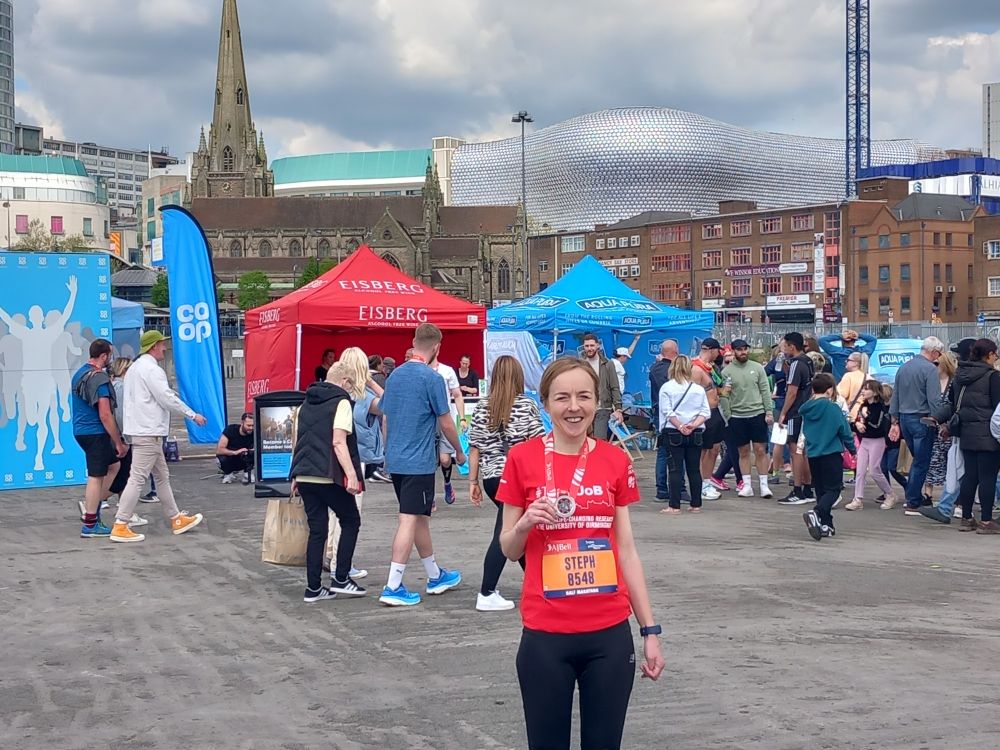 Person with a medal in front of the Birmingham skyline.