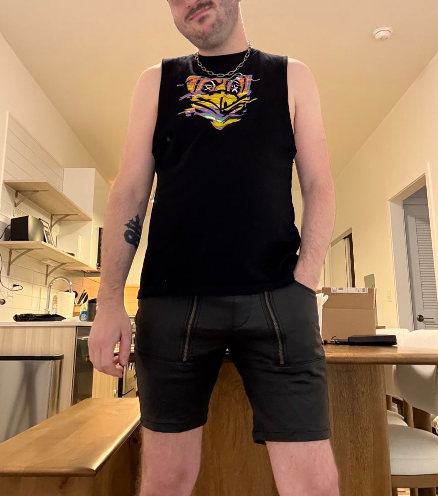 Man wearing black Fort Troff sleeveless shirt, black leather shorts, and silver chain