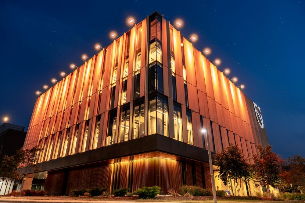 Shawenjigewining Hall illuminated with orange lights at dusk