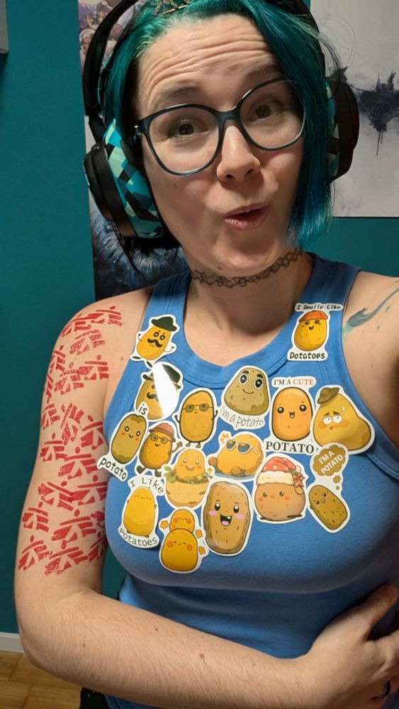 2DKiri wearing headphones, a tiara, lots of cute potato stickers on her top and a temporary tattoo sleeve out of Doctors Without Borders logos.
