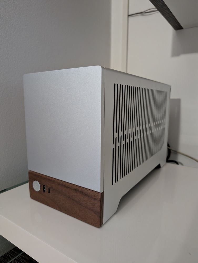 A Fractal Design Terra PC case in silver and dark wood. It's compact and has ventilation slits on the side.