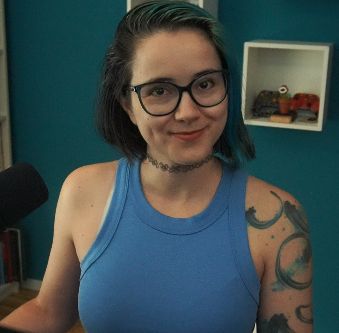 2DKiri sitting at her desk in her studio smiling. She's wearing a blue tank top.