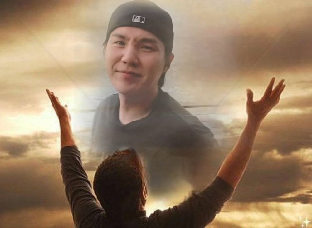Recent photo of Yoongi doing a cute nose scrunch but it’s photoshopped into a golden sky with a man holding his arms out wide open