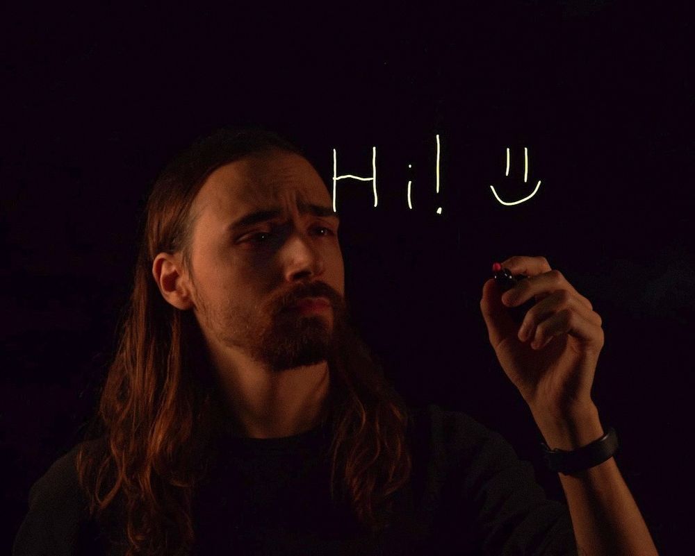 A photo of myself writing "Hi! :)" on a lightboard.