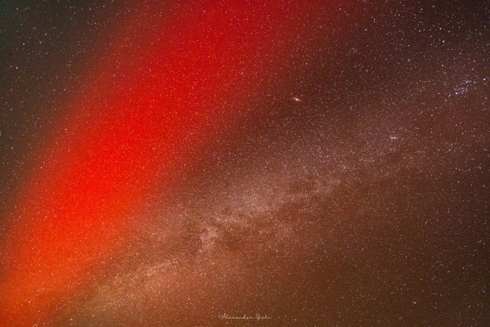 The andromeda galaxy between a red SAR arc and the Milky Way.