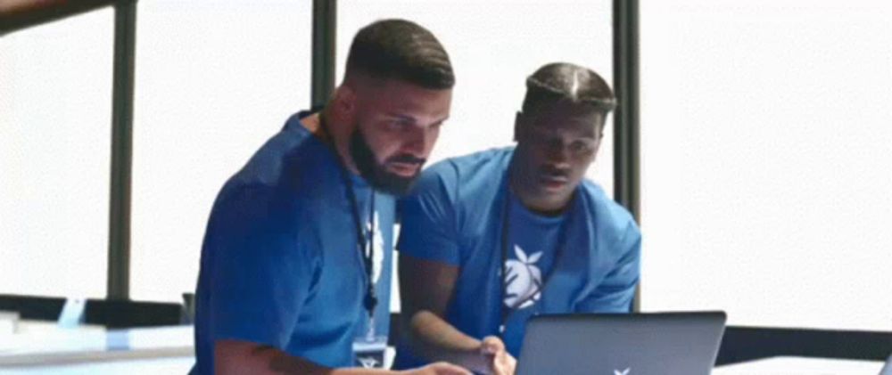 two men are looking at a laptop computer .