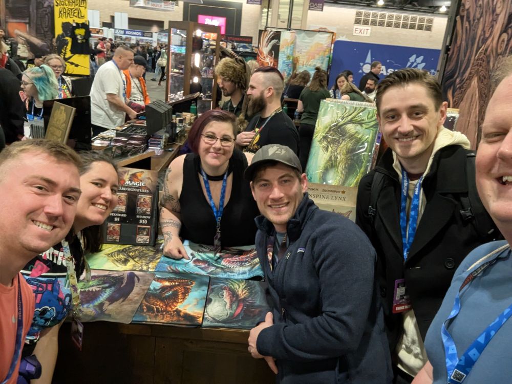 Five friends standing in front of a booth at PAX Unplugged with a woman selling her awesome dragon art.