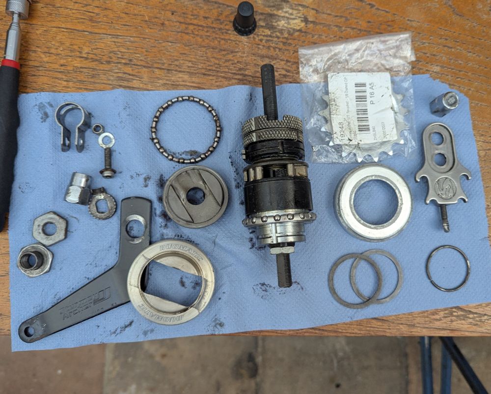 The internals of a Sturmey Archer S2C hub spread out on a sheet of blue roll paper. After about 5000 miles the shift was getting a bit tired and the brakes less reliable so I decided to replace the internal mechanism. For only two gears it sure does have a lot of parts. 