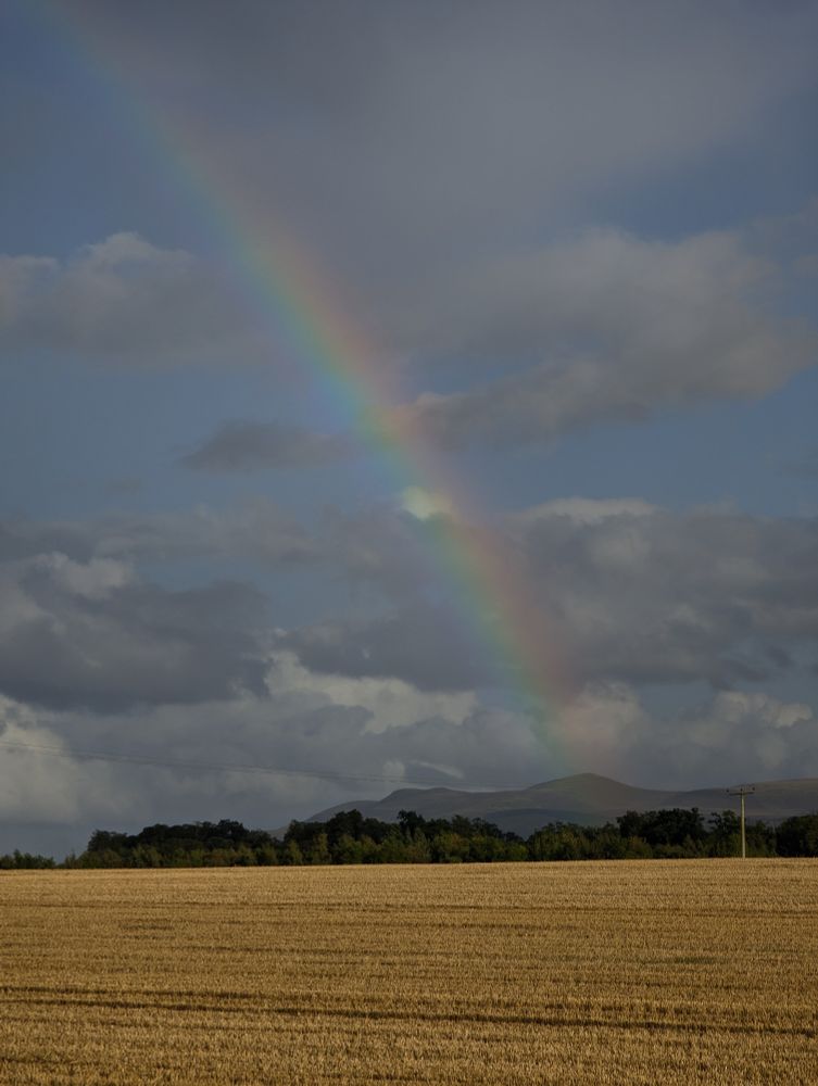 A wee rainbow above the sun lit stubble field. 