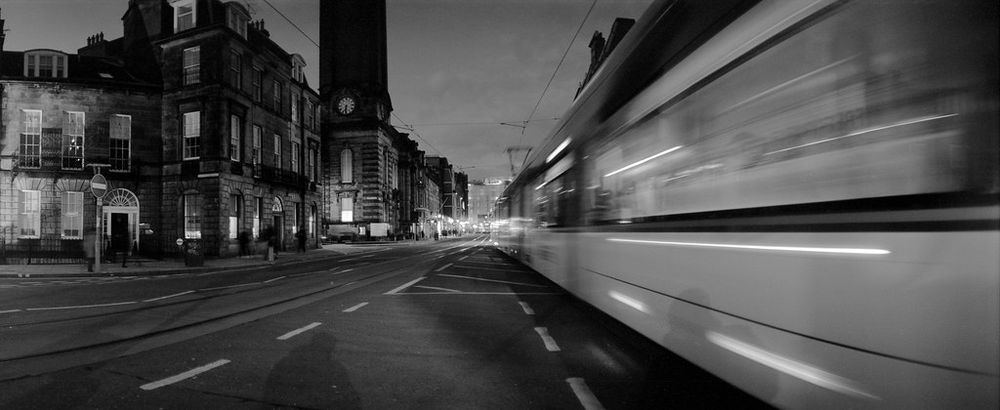 Black and white panoramic photo of an Edinburgh tram at Shandwick Place. The Horizon 202 is a swing lens camera so the movement of the tram is accentuated by the motion of the lens during the exposure. 