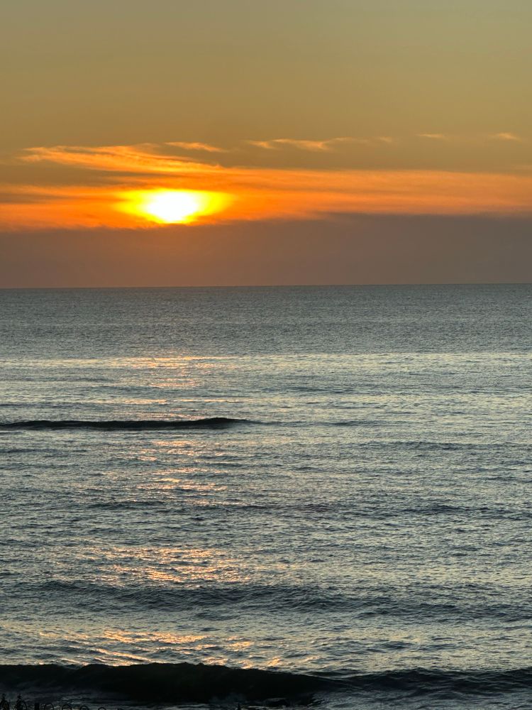 The sun rising above low cloud into a clear sky