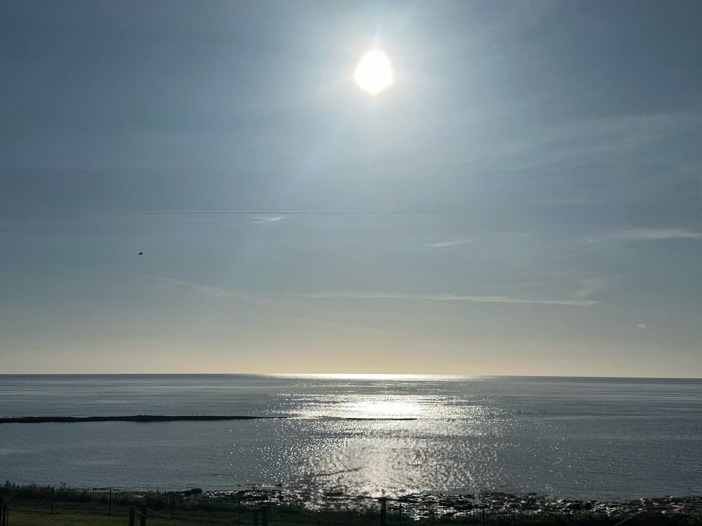 Clear sky, glistening sun, flat sea