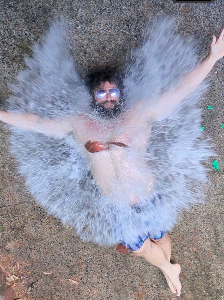 Still frame of water spread out over a man's chest as he gets hit by a water balloon from above.