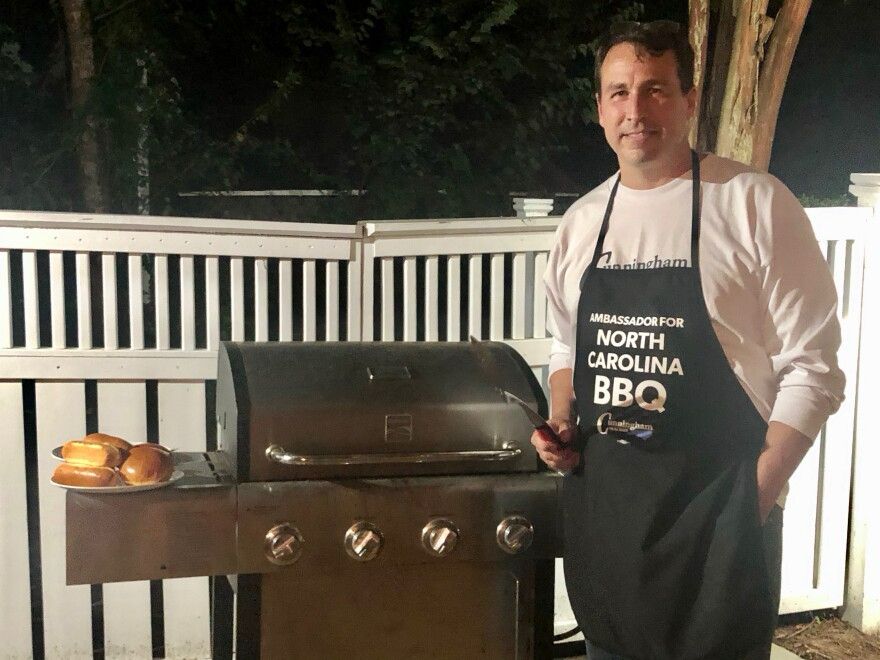 Look at this stupid motherfucker. He's standing next to a grill that is obviously not even on, he's wearing an apron that says "Ambassador for North Carolina BBQ" but there's a plate of hamburger and hotdog buns on the grill. NORTH CAROLINA BBQ IS PULLED PORK YOU STUPID SHIT. 