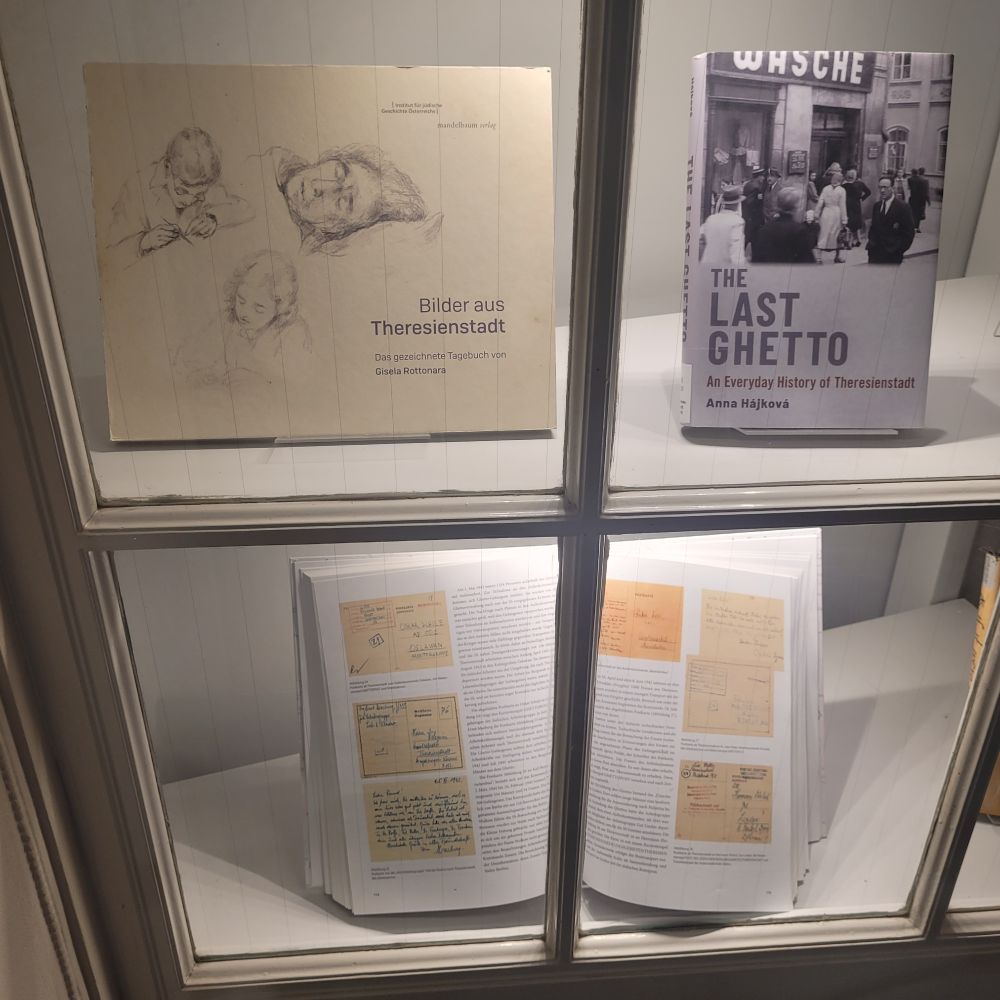 Drei Bücher, die Theresienstadt thematisieren, werden in einem beleuchteten Schaukasten präsentiert. 